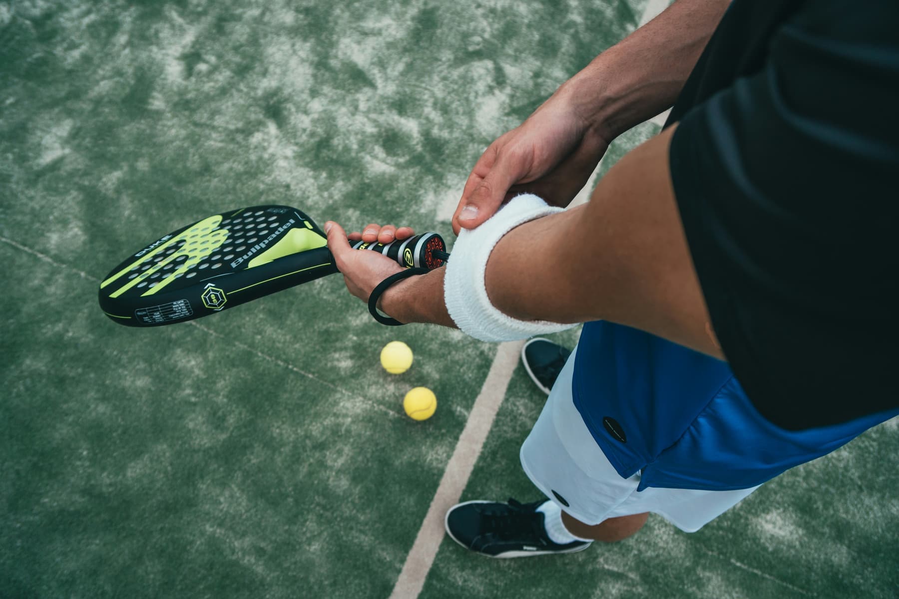 A padel racket in its cover beside a rulebook on a wooden table